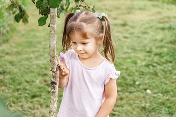 little girl near a young tree in nature