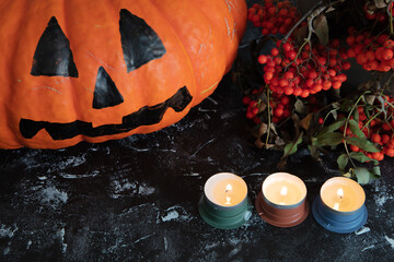 Halloween background. Pumpkin, candlesticks, red rowan, burning candles