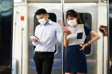 Wall Mural - Asian young woman use smart phone on Public Transport. Crowd of passengers on Urban Public Transport Metro. Face Mask protection against virus. Covid-19, coronavirus pandemic