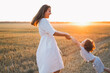 Woman playing with her child on the field during sunset.