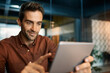 © mavoimages - Smiling businessman using a tablet at his office desk