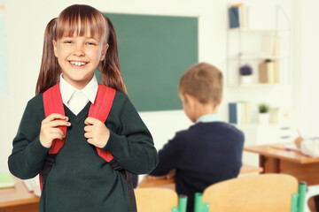 Wall Mural - Happy girl with backpack in school classroom