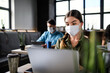 © Halfpoint - Business people with face masks indoors in office, back to work after coronavirus lockdown.