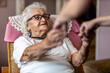 © pikselstock - Female home carer supporting old woman to stand up from the armchair at care home
