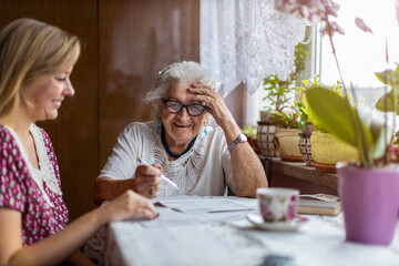 Young woman helping elderly grandmother with paperwork
