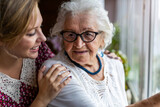 Fototapeta  - Young woman spending time with her elderly grandmother at home
