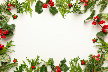 Wall Mural - Christmas background with branches of fir tree, evergreens and holly with red berries on white. Winter nature concept. Flat lay, copy space.