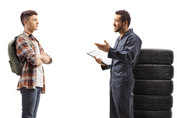 Wall Mural - Auto mechanic standing next to car tires and talking to a student