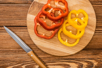 Wall Mural - top view of colorful sliced bell peppers on wooden cutting board near knife