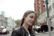 © darakaliton - the girl looking flirtatiously at the camera. Young woman with blonde hair wearing leather jacket. Model with windy hair looking at camera and smiling.
