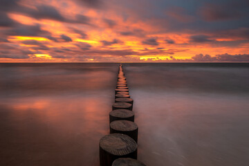 Wall Mural - minimalist landscape showing sea waves and a breakwater at sunset