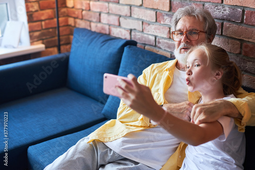 Cuadros en Lienzo modern grandfather having fun with granddaughter, they take photo on smartphone