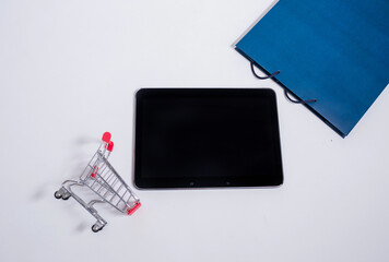 Tablet with a metal basket and a blue bag on a white background