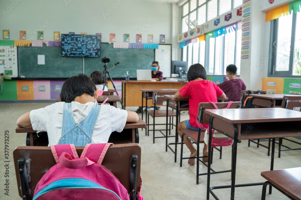 Group of elementary school student with teacher sitting in classroom ...