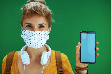 Wall Mural - student woman in shirt showing smartphone blank screen on green