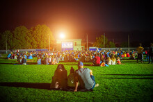 Summer Cinema. People And Couples Watching A Movie On The Screen Of A Summer Cinema In The Evening