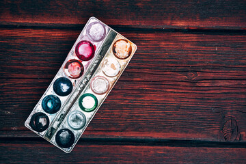 Art Palette with empty Colorful Paints Close up on a mahogany table. Empty and used multi-colored paint.