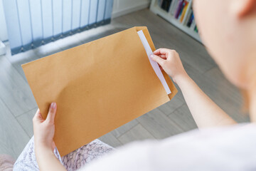 Close up on hands of unknown caucasian woman hold envelope opening or sending letter with mail or documents at home in day top view