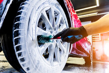 Cleaning The Car Wheel With A Brush And Water