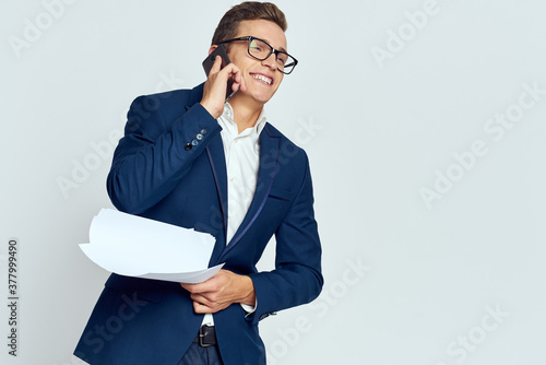 Fotografía Business man in a suit talking on the phone with glasses with documents technolo