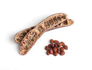 Wall Mural - empty carob pods and poured seeds heap, top view, isolated on white background