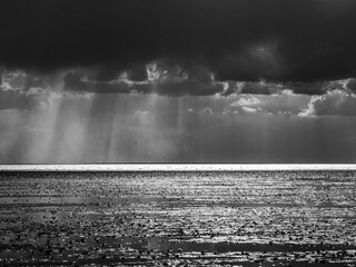 Wall Mural - greyscale shot of the sunrise in the dark cloudy sky over the ocean