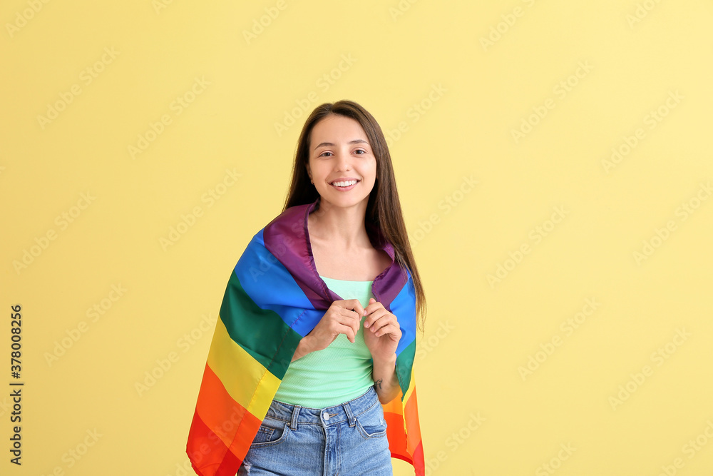 Young woman with LGBT flag on color background