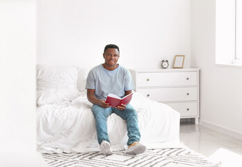 Wall Mural - African-American man reading book at home