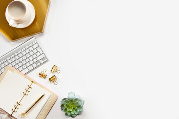 Top view of stylish office desk accessories with keyboard and cup of cappuccino on the gold tray.