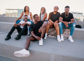 group of young modern african black friends happily sitting together on the bench of the stairs in b