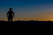 © Paloma - silhouette of a woman from the front with her arms on her hips in a sunset with the sky divided by yellow and blue