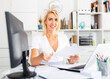 © JackF - Smiling woman working with papers and laptop in office