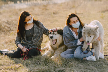 Wall Mural - Women in a masks in a spring forest. Girls with cute dogs. Corona virus.