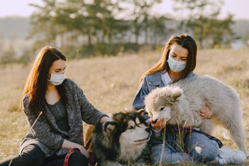 Wall Mural - Women in a masks in a spring forest. Girls with cute dogs. Corona virus.