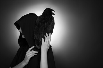 Mysterious witch with raven on dark background, space for text. Black and white effect