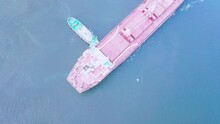 Two Tugs Are Doing Work On Mooring A Large Cargo Ship For Loading Grain At The Seaport Berth. The Ship Is Sailing On The Calm Blue Sea On A Sunny Summer Day. Aerial View Bird's-eye View. Drone. Quadco