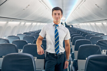 Young man standing in the empty board of commercial airplane