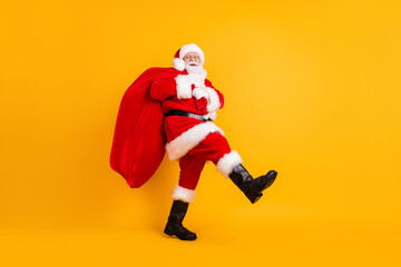 Wall Mural - Full length body size profile side view of his he nice funny cheerful white-haired Santa St Nicholas going carrying big large sack sale shop isolated bright vivid shine vibrant yellow color background