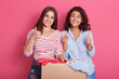 © sementsova321 - Smiling young women posing near box full of clothes, showing thumb up recommend donating apparel to needy people, happy females stack good things in charity package, clothing for reuse.