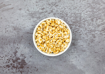 Wall Mural - Honey puffed wheat in a bowl on a mottled gray background