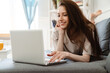 © Drobot Dean - Photo of joyful beautiful girl working with laptop while lying on couch