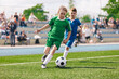 © matimix - Young boys playing soccer game. Kids having fun in sport. Happy kids compete in football game. Running soccer players. Competition between players running and kicking football ball. Football school