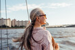 © Artem Varnitsin - Side view of mature woman wearing sunglasses and looking to the distance while standing on the yacht