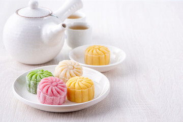 Colorful snow skin moon cake, sweet snowy mooncake, traditional savory dessert for Mid-Autumn Festival on bright wooden background, close up, lifestyle.