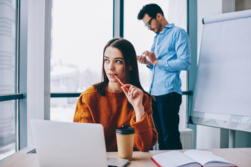 Wall Mural - selective focus on skilled female employee sitting at table desktop and thinking about laptop projec