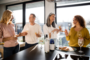 Wall Mural - Happy adult women and man enjoying wine at home