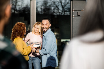 Happy adult man standing near two ladies outdoors