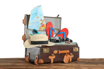 Wall Mural - Open vintage suitcase with clothes packed for summer vacation on wooden table against white background