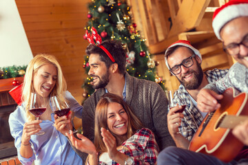 Wall Mural - Friends playing the guitar, singing Christmas songs and drinking wine