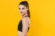 © ViDi Studio - Side view of smiling young fitness sporty woman 20s wearing black sportswear posing training working out standing looking camera isolated on bright yellow color wall background studio portrait.